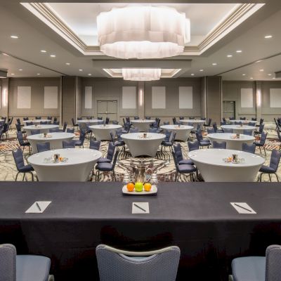 A conference room is set up with round tables and chairs, and a long table at the front, ready for a meeting or presentation, ending the sentence.