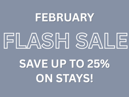 A February flash sale sign on a muted blue-gray background, promoting up to 25% off on stays.