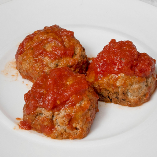 Three meatballs topped with red marinara sauce on a white plate.